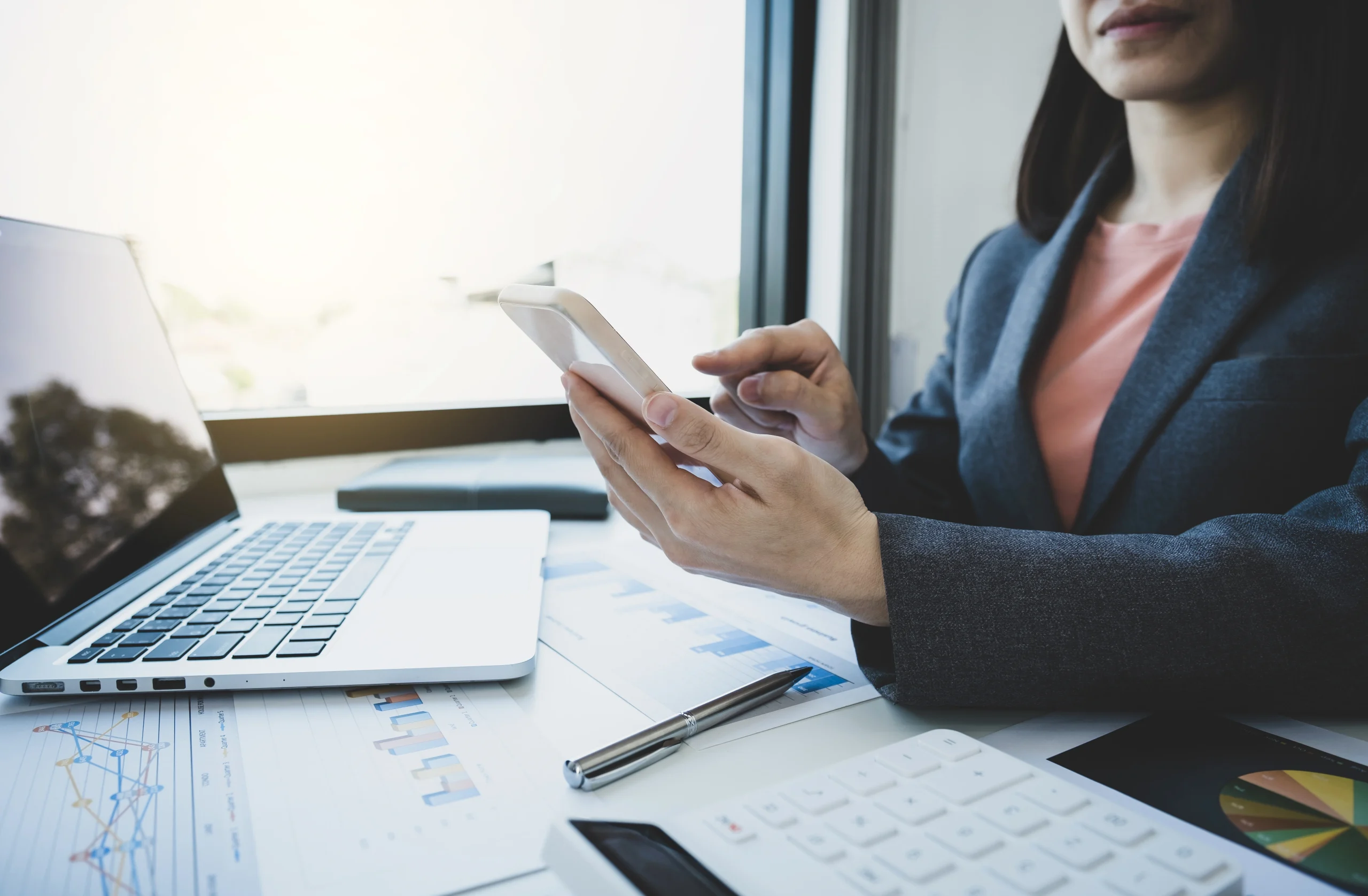 A business professional analyzes accounting data on a smartphone at their desk