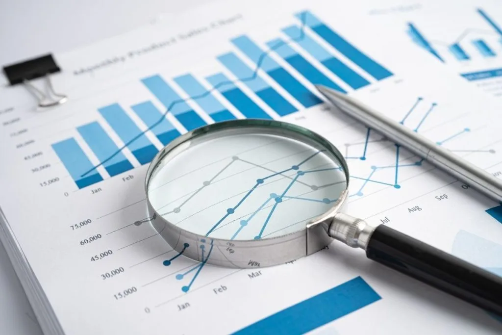 A magnifying glass emphasizes blue graphs and data about the report's findings
