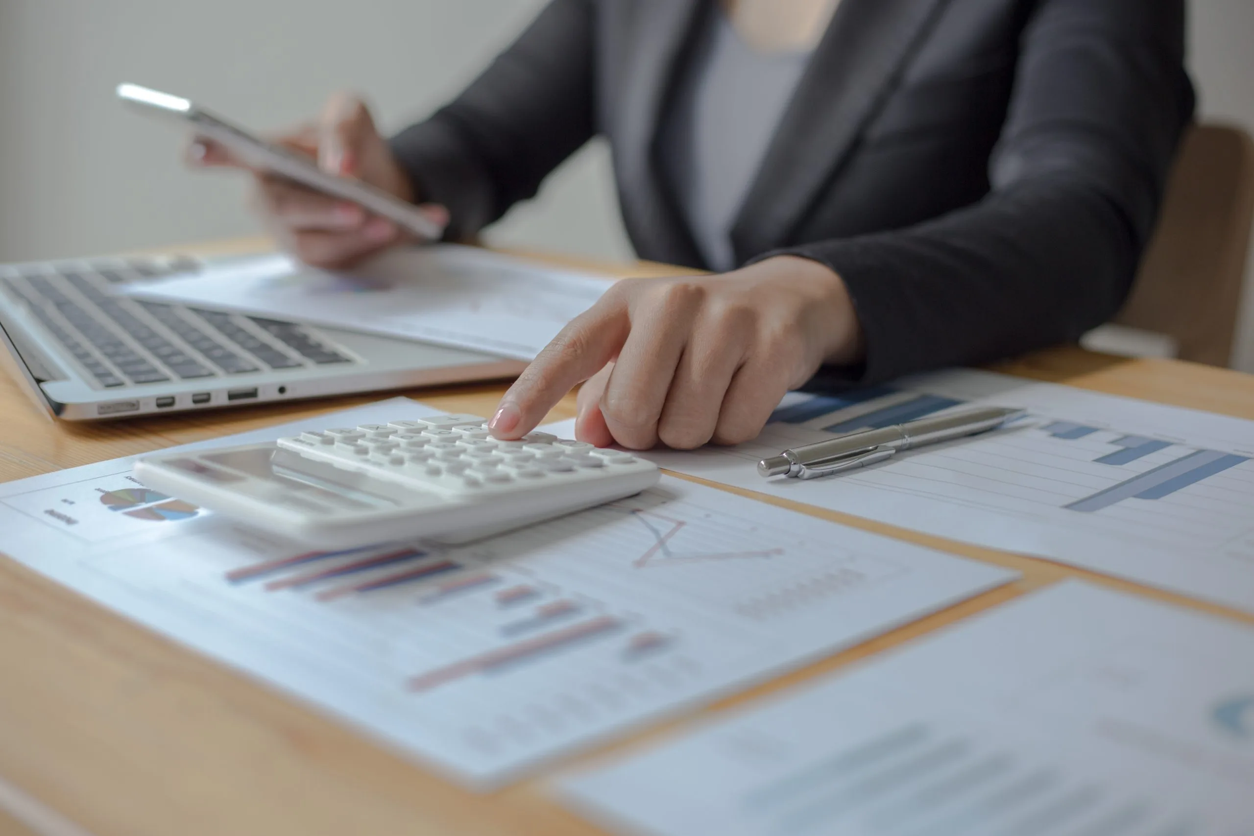 Tax preparation involves a professional calculating figures on a laptop with documents nearby