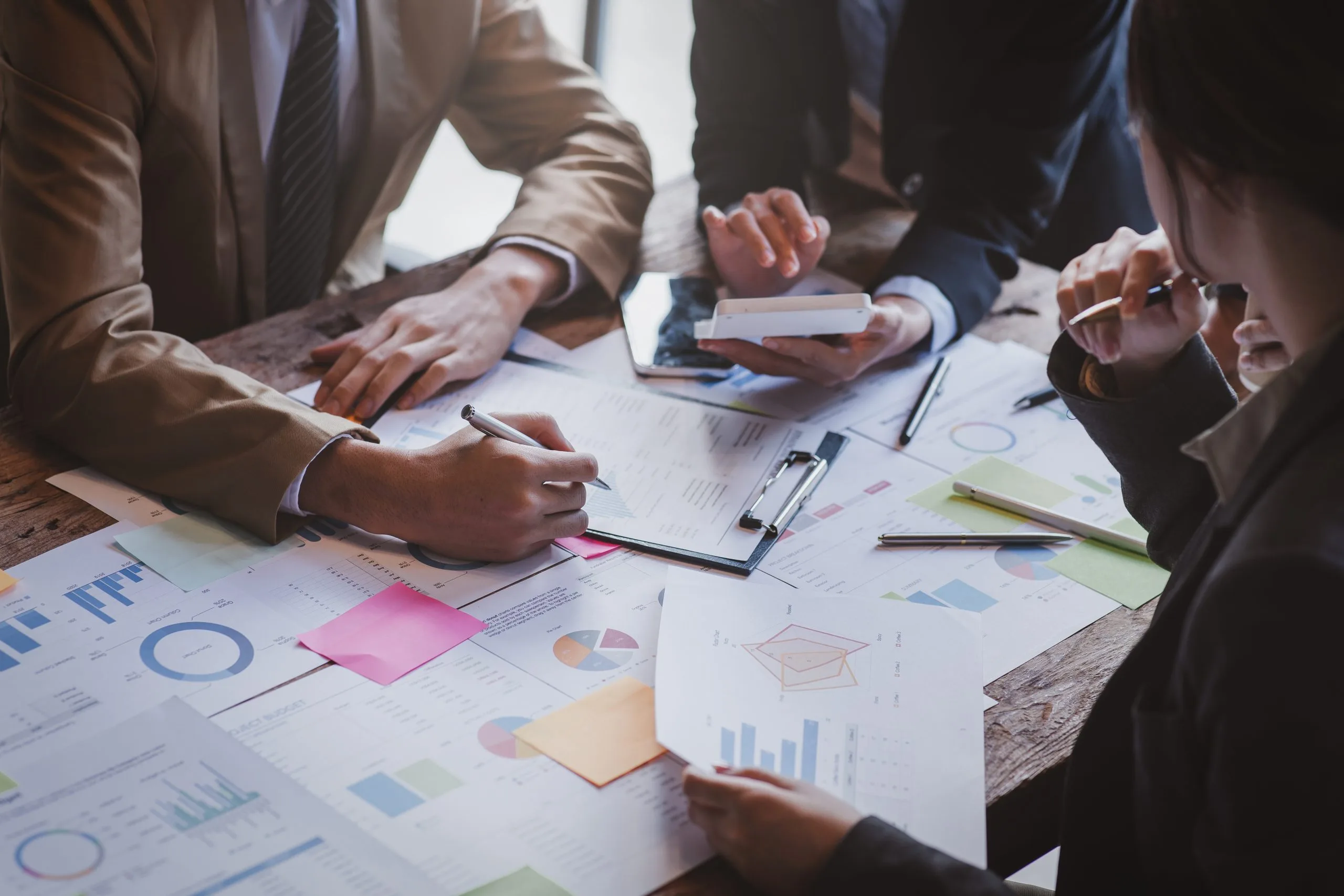 Business valuation discussions take place as people collaborate around a table with documents and charts