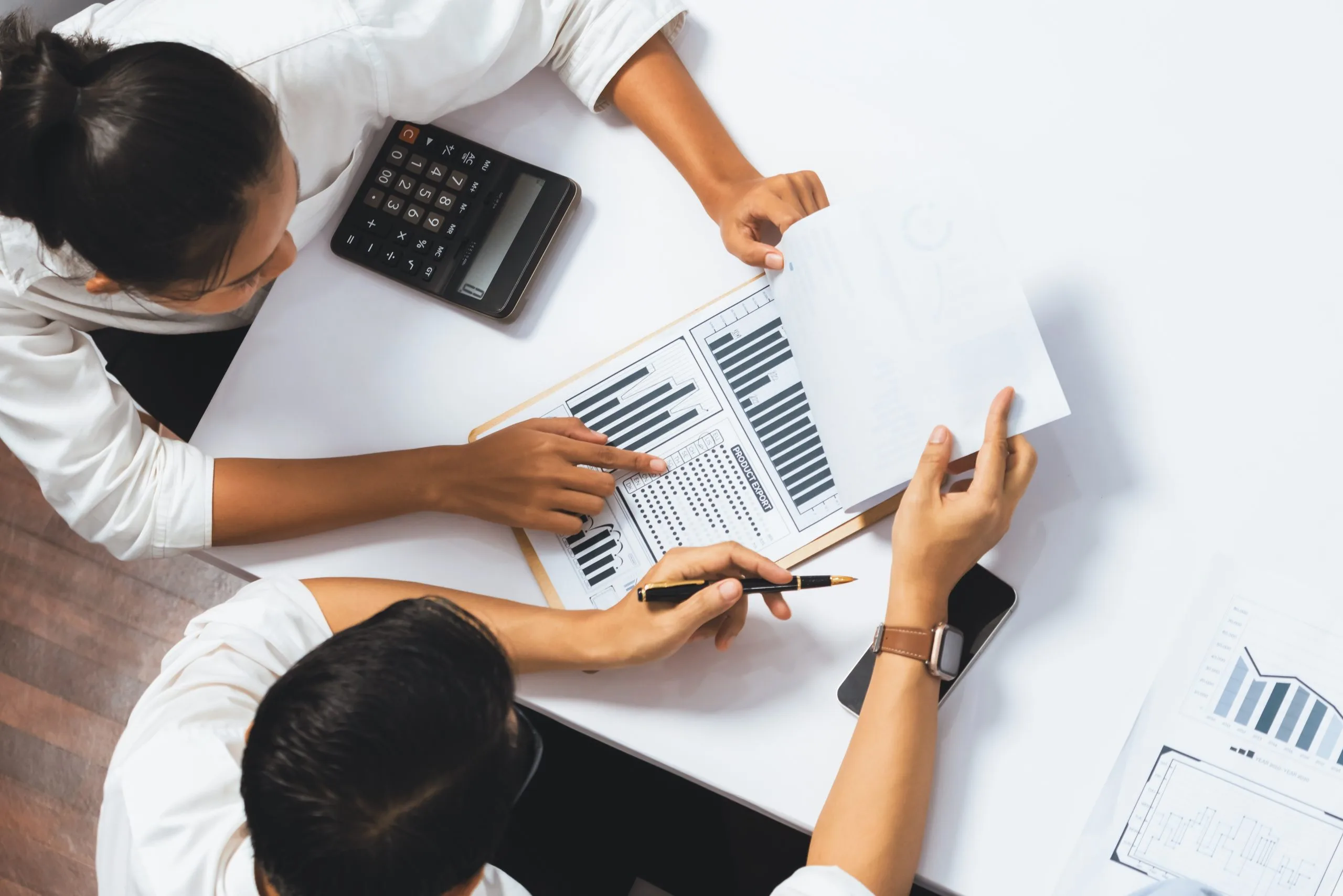 Bookkeeping professionals collaborate on charts and data analysis at a table