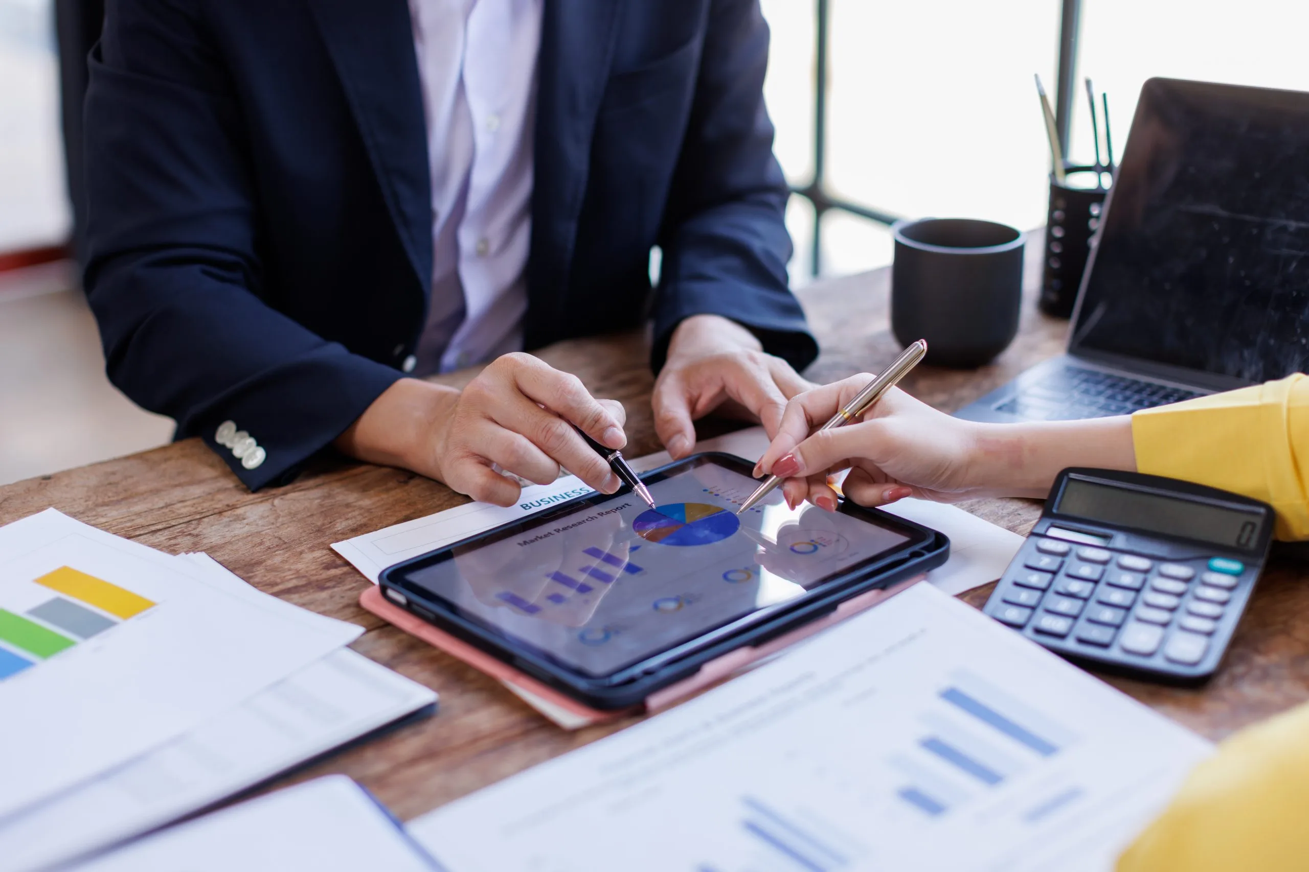 Bookkeeping collaboration on a tablet with graphs and charts, surrounded by documents